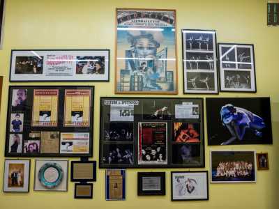Entriamo in uno stretto corridoio giallo colmo di locandine di eventi, articoli di giornale, premi di concorsi e foto storiche